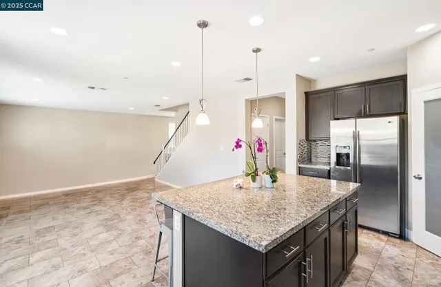 a kitchen with granite countertop kitchen island stainless steel appliances a sink cabinets and refrigerator