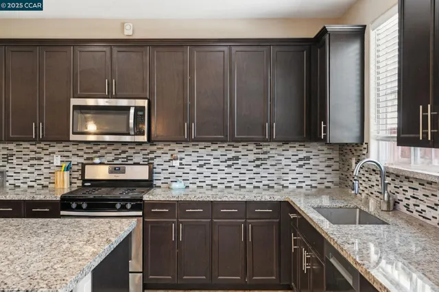 a kitchen with granite countertop a sink a stove a microwave and cabinets