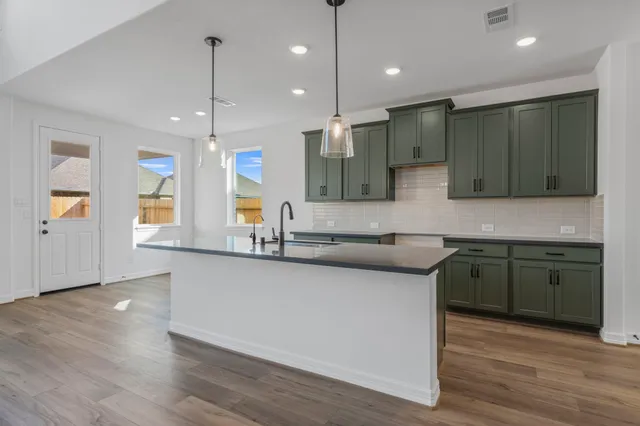 a view of a kitchen with kitchen island a sink wooden floor and a counter top space