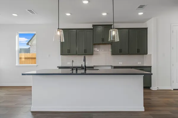 a view of a kitchen with kitchen island a sink wooden floor and a counter top space