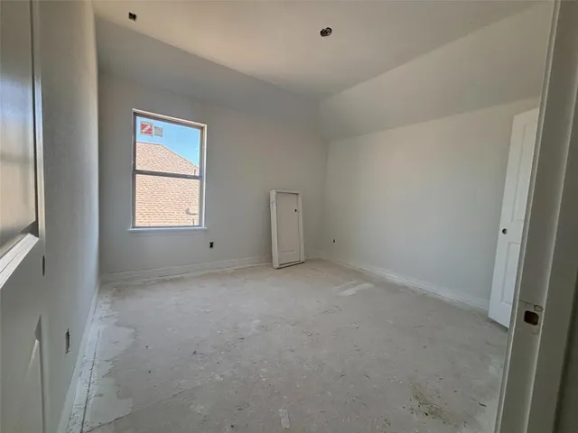 an empty room with a window and a kitchen