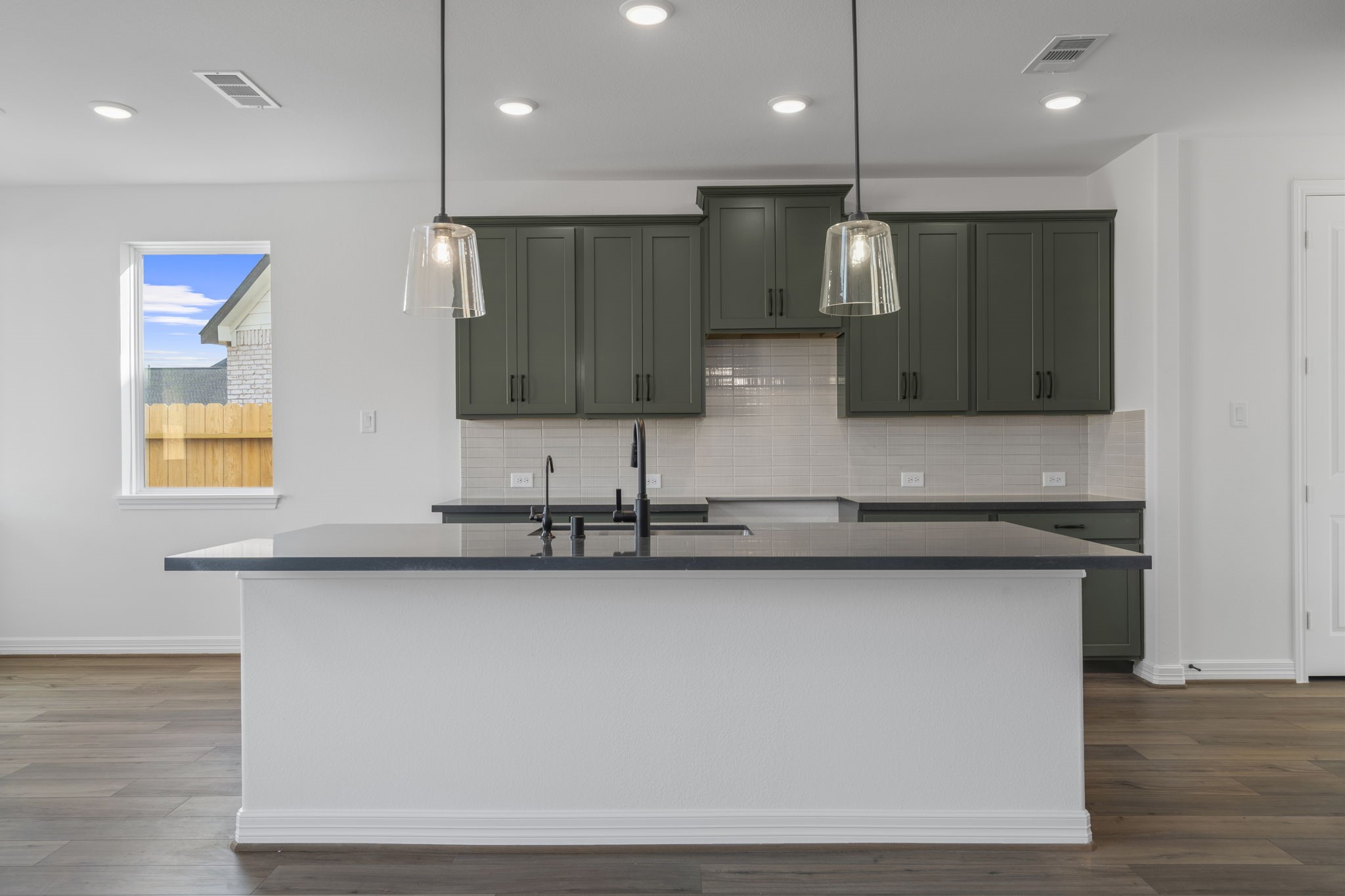 7822 Jasper Meadows Way Angleton, TX 77515 - Photo 8 of 33 a view of a kitchen with kitchen island a sink wooden floor and a counter top space