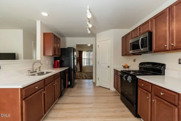 a kitchen with stainless steel appliances granite countertop wooden cabinets a sink dishwasher a stove and a refrigerator
