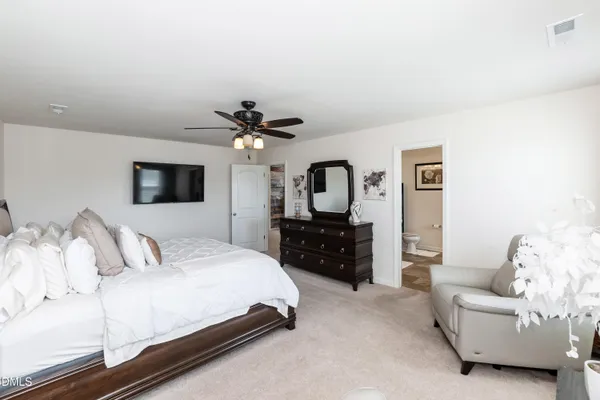 a bedroom with a bed couches and a flat tv screen