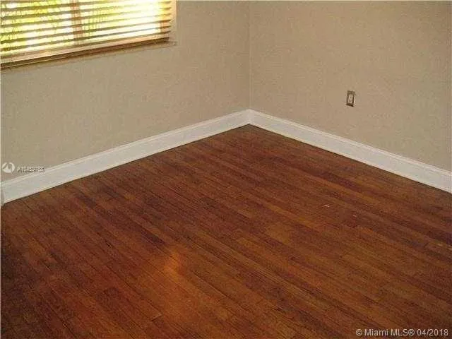 a view of a room with wooden floor and a window