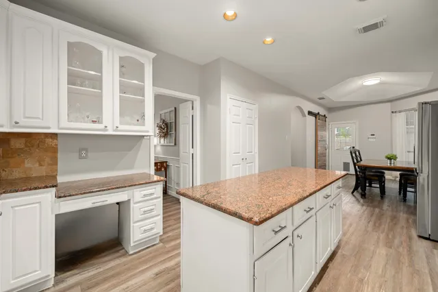 a kitchen that has a lot of cabinets in it and wooden floors