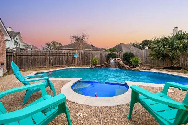 a view of a swimming pool with a patio and a yard
