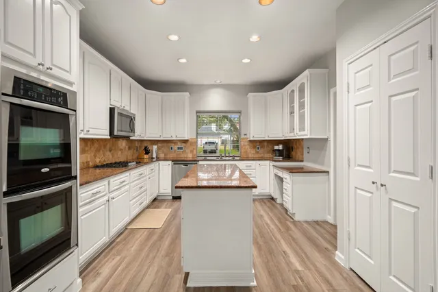 a kitchen with stainless steel appliances granite countertop a refrigerator a stove top oven a sink and dishwasher with wooden floor