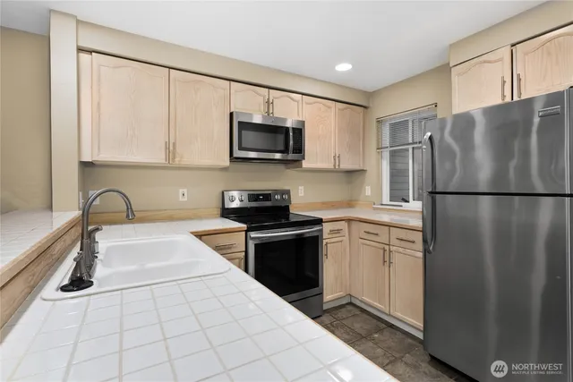a kitchen with stainless steel appliances granite countertop a refrigerator sink and stove