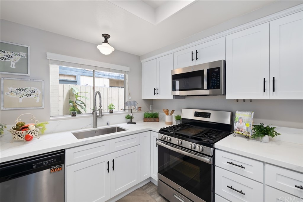 a kitchen with granite countertop white cabinets white stainless steel appliances and sink