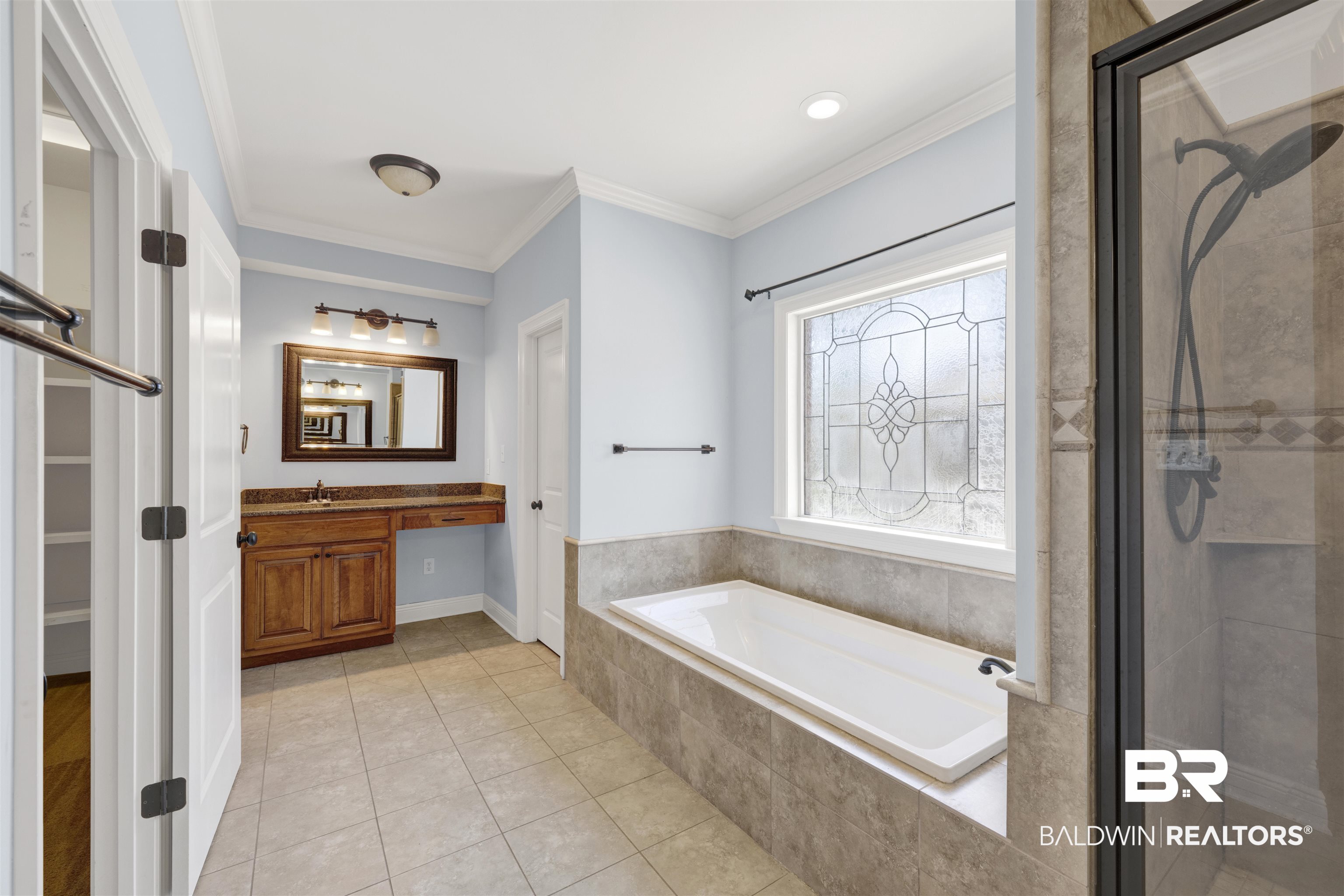 12944 Anna's Way Stapleton, AL 36578 - Photo 51 of 64 Full bathroom featuring a built-in soaking tub, a separate glass-enclosed shower, a wood-finish vanity with a stone-finish countertop, and a decorative frosted window
