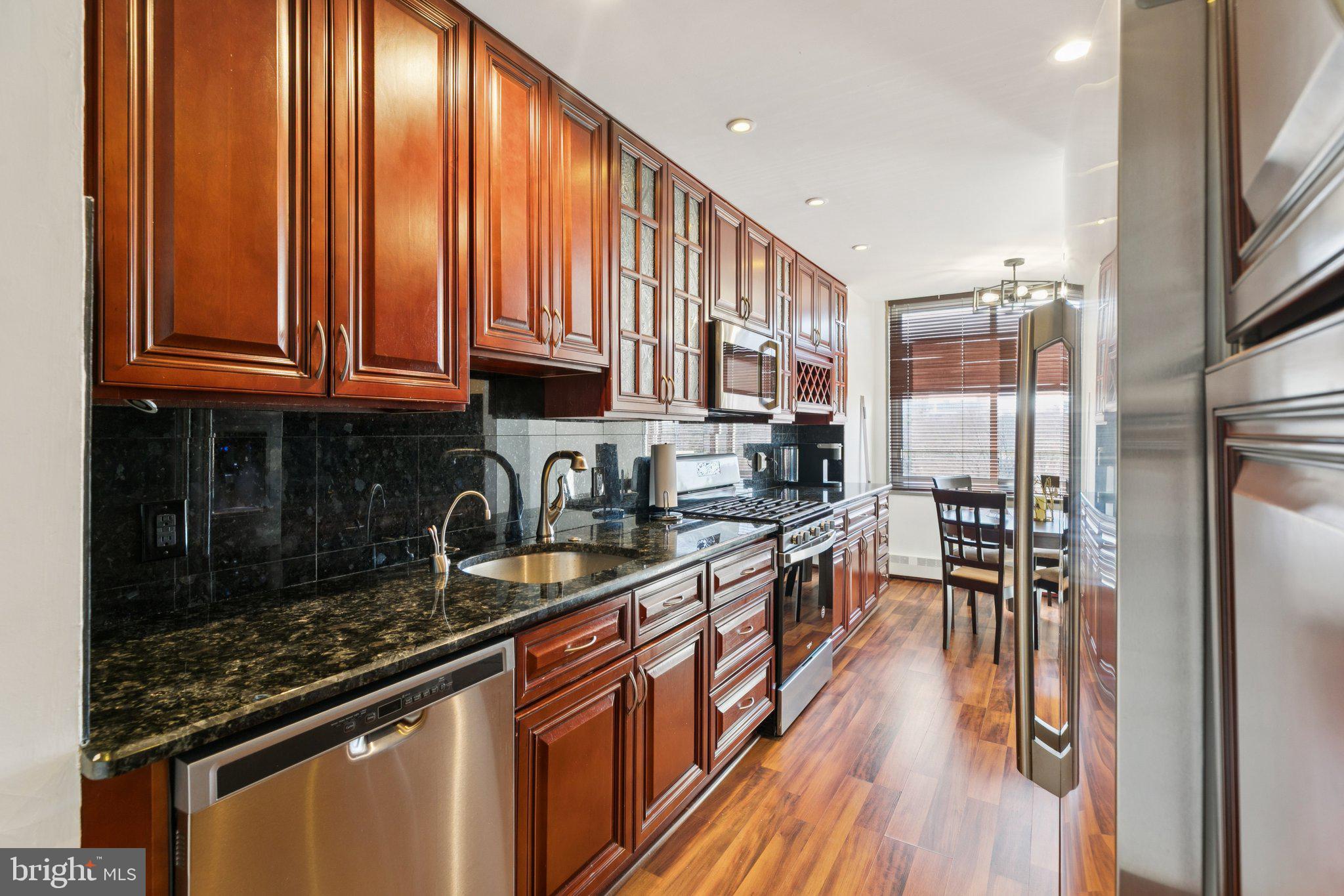 191 Presidential Boulevard, Unit R724 Bala Cynwyd, PA 19004 - Photo 6 of 19 an open kitchen with granite countertop stainless steel appliances and wooden cabinets