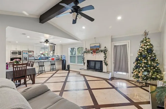 a living room with furniture a dining table with kitchen view and a chandelier