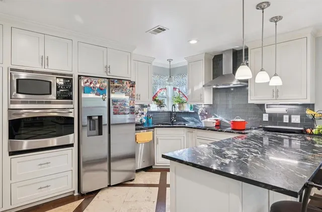 a kitchen with stainless steel appliances granite countertop a sink a stove and a refrigerator