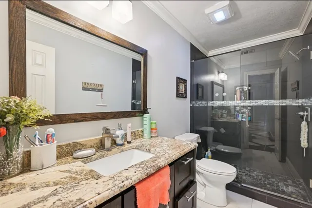 a bathroom with a granite countertop sink mirror vanity and toilet