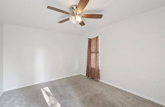 an empty room with a ceiling fan and a window