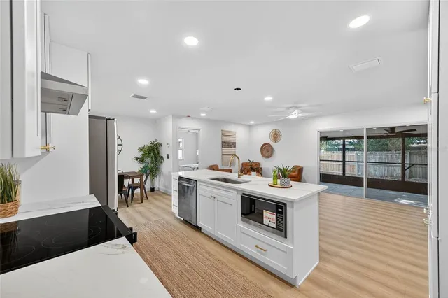 a large room with stainless steel appliances lots of white furniture a dining table and chairs