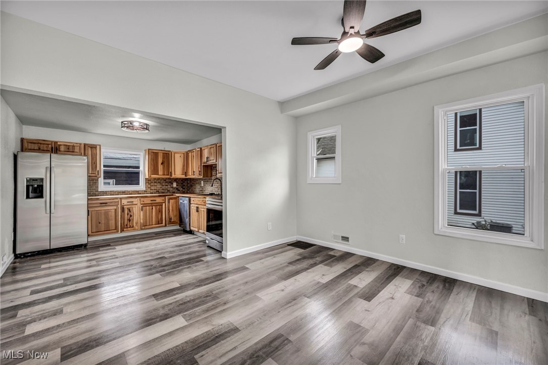 397 Furnace Road Conneaut, OH 44030 - Photo 11 of 36 Kitchen featuring appliances with stainless steel finishes, wood finished floors, brown cabinets, ceiling fan, and decorative backsplash