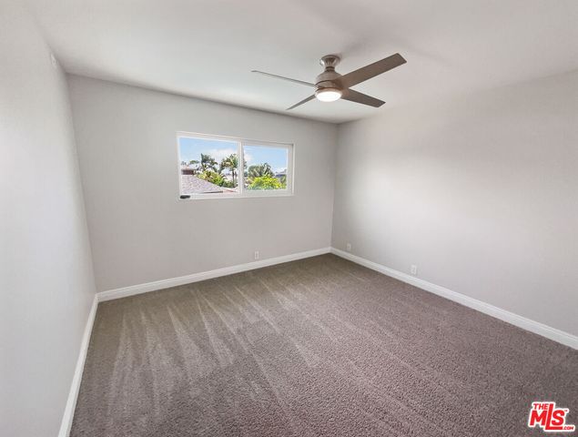 an empty room with a window and ceiling fan