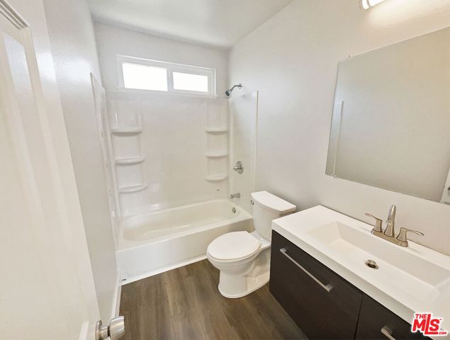 a bathroom with a bathtub shower sink mirror vanity and toilet