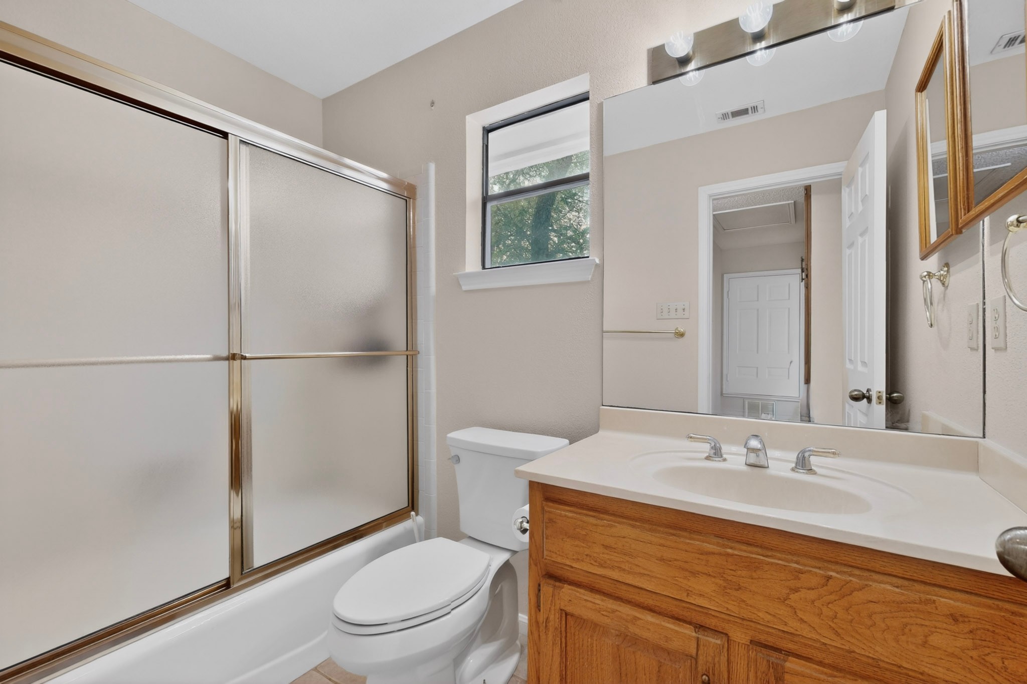 1003 Pier Branch Road Dripping Springs, TX 78620 - Photo 28 of 40 A window-lit bathroom featuring a tub with sliding doors and a vanity with a large mirror.
