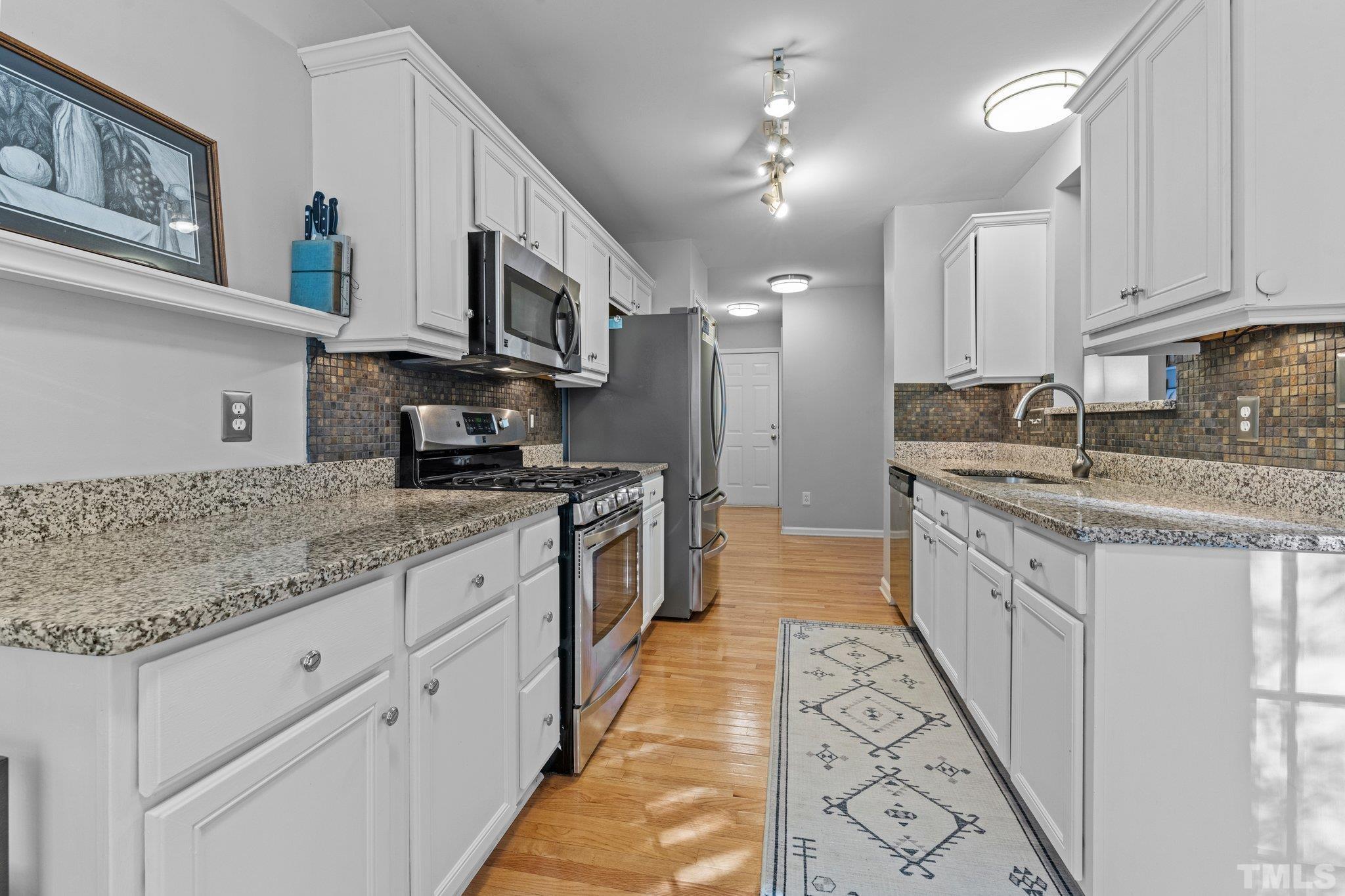 1405 Lynn Road Raleigh, NC 27612 - Photo 11 of 33 a kitchen with stainless steel appliances granite countertop a sink stove oven a refrigerator with white cabinets and couches