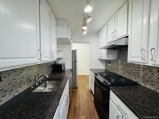 a kitchen with granite countertop a sink a stove and refrigerator