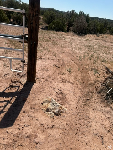 475 South Willey Road Duchesne, UT 84021 - Photo 21 of 22 Rustic wooden fence post with a white metal gate, set against a natural landscape featuring sparse vegetation and distant trees