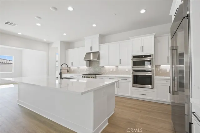 a kitchen with stainless steel appliances a sink stove refrigerator and cabinets
