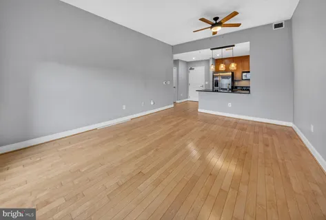 a view of empty room with wooden floor and fan