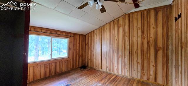 11785 Milam Road Colorado Springs, CO 80908 - Photo 29 of 44 Spare room with hardwood / wood-style flooring, wood walls, ceiling fan, and lofted ceiling