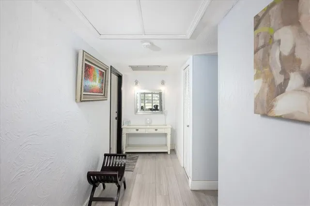 a view of a hallway to a room with wooden floor and windows