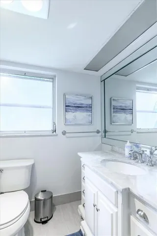 a bathroom with a granite countertop toilet sink and mirror