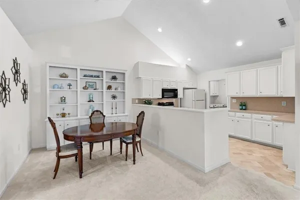 a kitchen with a dining table chairs and refrigerator