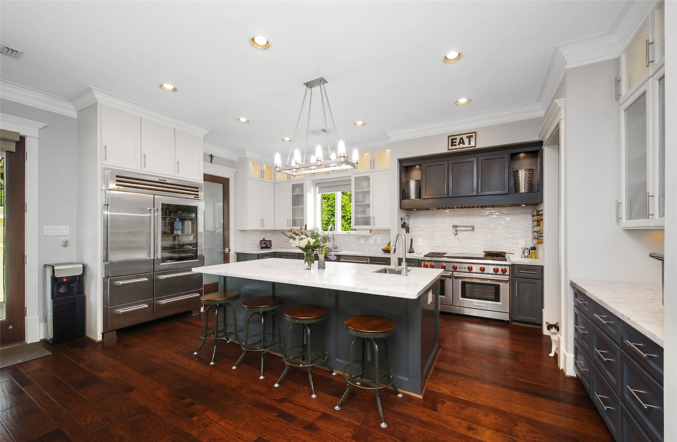 416 West 33rd Street Houston, TX 77018 - Photo 11 of 47 Chef-inspired kitchen thoughtfully designed for elevated everyday living, featuring an oversized quartz island with seating, custom cabinetry, premium stainless appliances and a coveted Wolf gas range with built-in griddle. Designer lighting, abundant prep space and rich hardwood floors complete this sophisticated gathering space at the heart of the home. Cat not included.