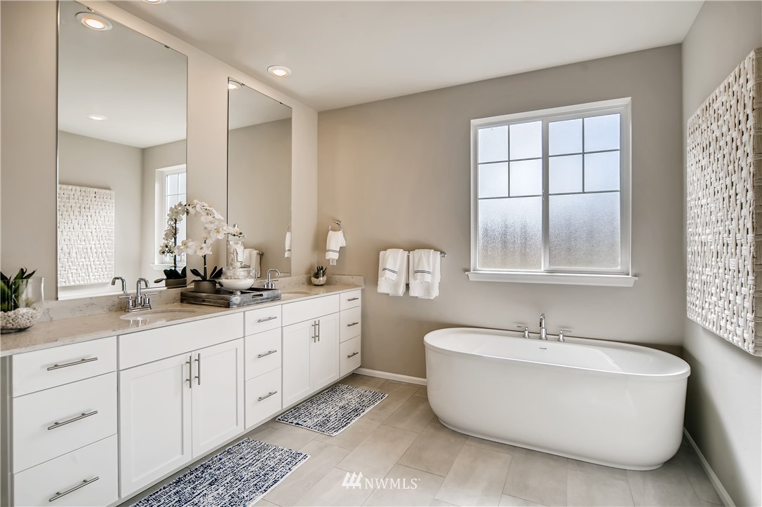 8812 Northeast 199th Street, Unit 1 Bothell, WA 98011 - Photo 11 of 31 a bathroom with double vanity sinks a large mirror and a bathtub