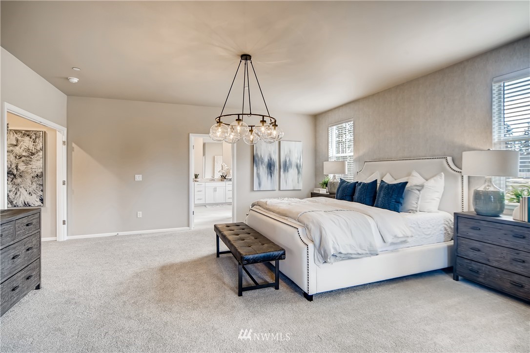 8812 Northeast 199th Street, Unit 1 Bothell, WA 98011 - Photo 28 of 31 a spacious bedroom with a bed chandelier and a window