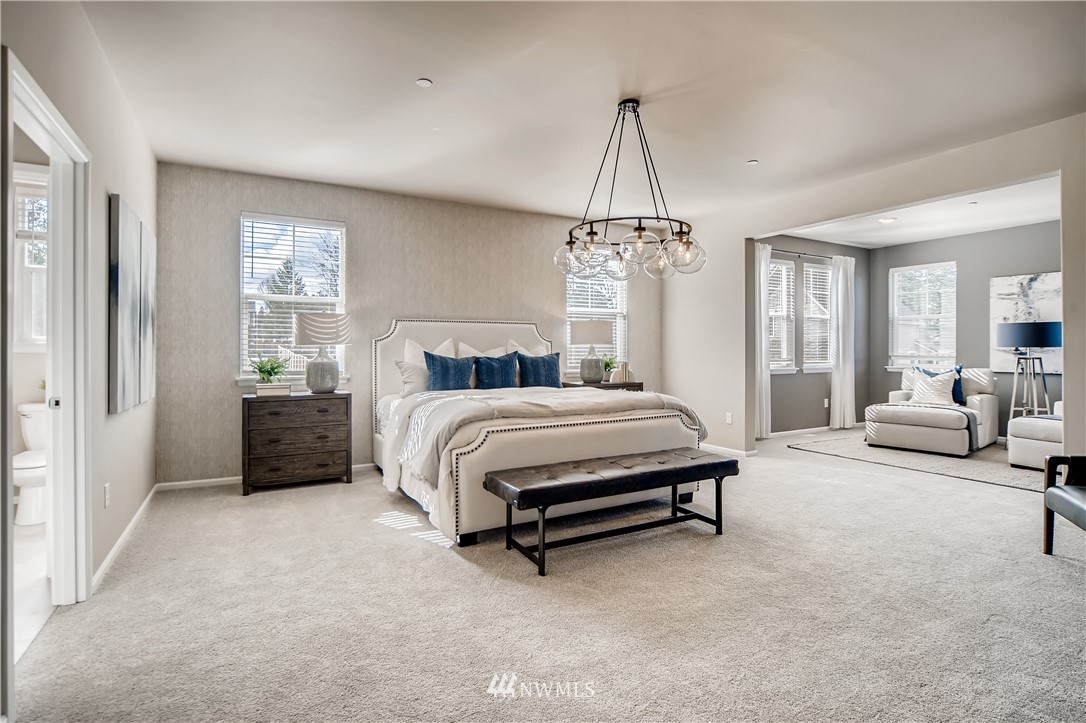 8812 Northeast 199th Street, Unit 1 Bothell, WA 98011 - Photo 10 of 31 a spacious bedroom with a bed a table and to chandelier