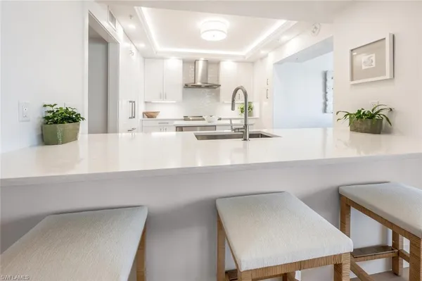a kitchen with sink stove and white cabinets with wooden floor