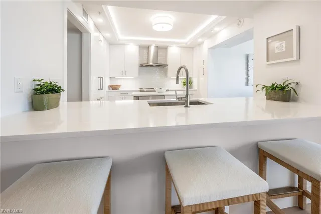 a kitchen with sink stove and white cabinets with wooden floor