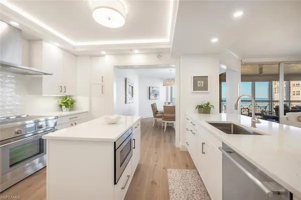 a kitchen with a stove a sink dishwasher and white cabinets with wooden floor