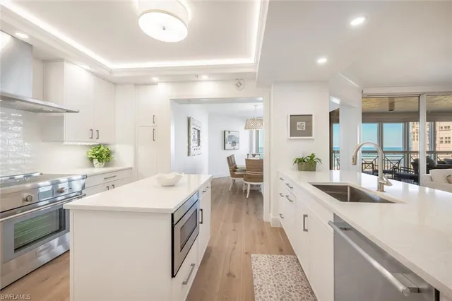 a kitchen with a stove a sink dishwasher and white cabinets with wooden floor