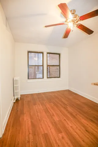 a view of an empty room with window and wooden floor