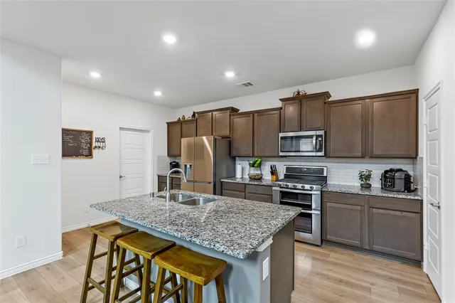 a kitchen with kitchen island stainless steel appliances a sink stove and refrigerator