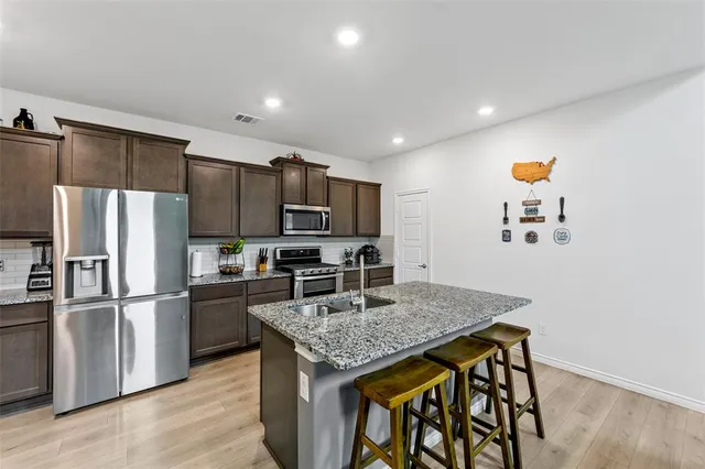 a kitchen with stainless steel appliances granite countertop a refrigerator a stove a sink and a refrigerator