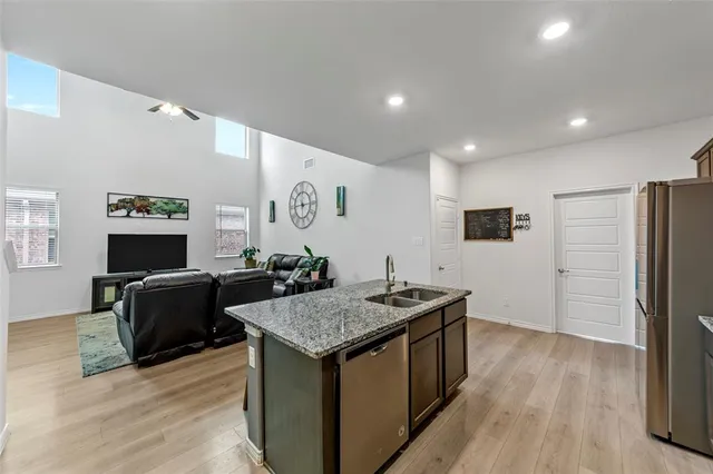 a living room with stainless steel appliances granite countertop furniture wooden floor and a table