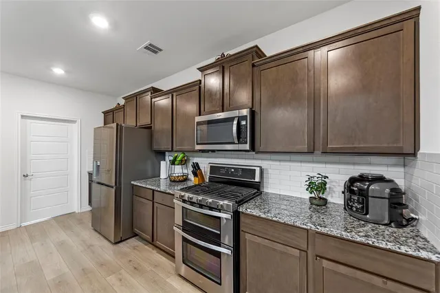 a kitchen with granite countertop stainless steel appliances and wooden cabinets