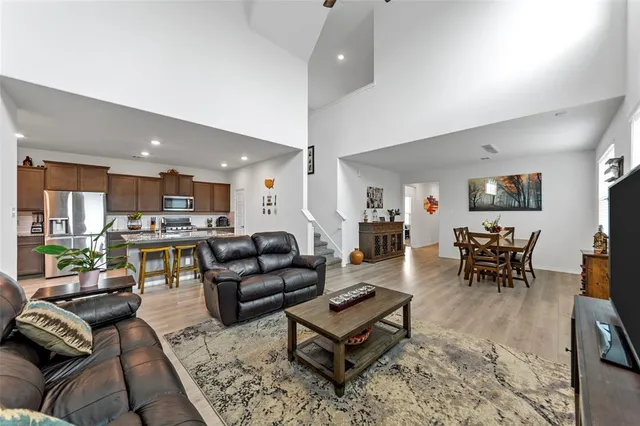 a living room with furniture kitchen view and a wooden floor