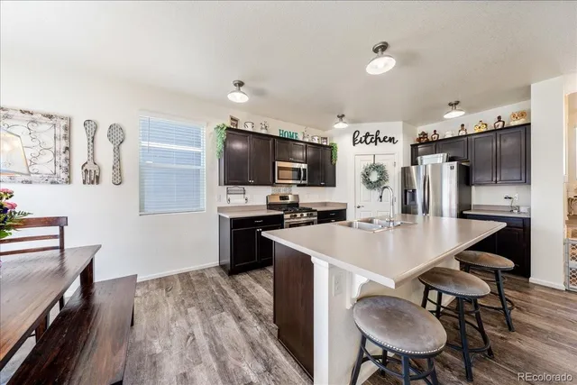 a kitchen with stainless steel appliances a dining table chairs stove refrigerator and cabinets