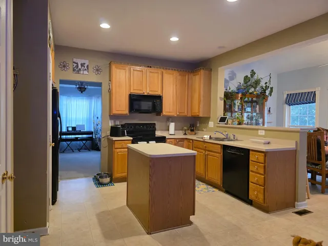 a kitchen with kitchen island granite countertop a stove top oven a sink a counter top space and cabinets